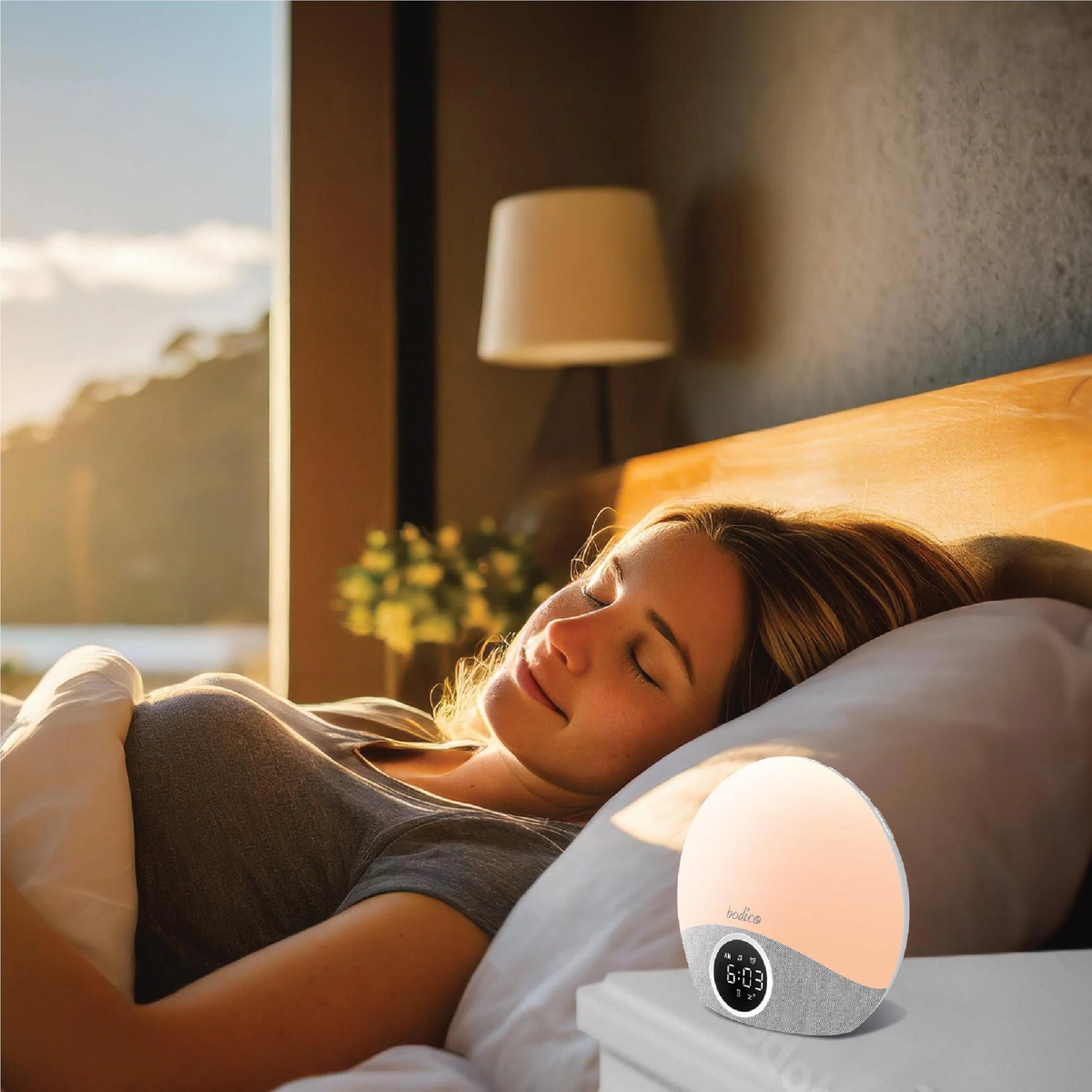 Woman lying in bed with a sunrise simulator on a nightstand
